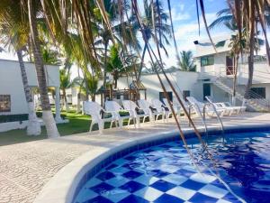 a pool with chairs and palm trees in front of a house at Cabañas La Fragata in Coveñas