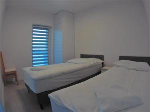 Cette chambre comprend 2 lits et une fenêtre. dans l'établissement Apartament Miedzianka II, à Polkowice