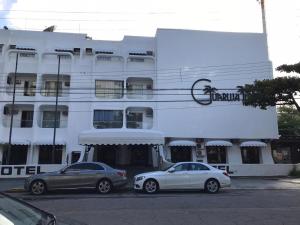 two cars parked in front of a white building at Hotel Guarujá Inn Tropical in Guarujá