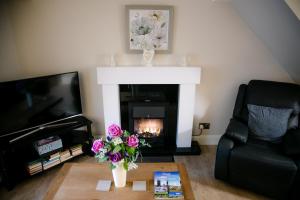 a living room with a fireplace and a vase of flowers at Eske Holiday Apartment in Donegal