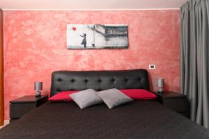 a bedroom with a black bed and a pink wall at The Roof - Appartamento con terrazza al centro di Civitavecchia in Civitavecchia