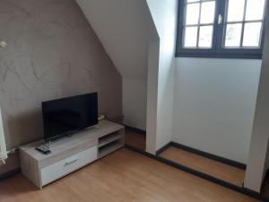 uma sala de estar com uma televisão de ecrã plano numa cómoda em Chambre de la Vigne em Blesmes