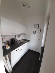 eine Küche mit weißen Schränken und schwarzem Boden in der Unterkunft Apartment in zentraler Lage Kassels in Kassel