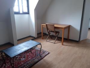 uma mesa e uma cadeira num quarto com um tapete em Chambre de la Vigne em Blesmes