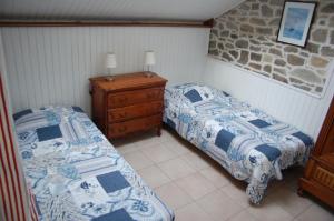 a bedroom with two beds and a wooden dresser at gîte marin petit châtelet in Hirel