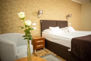 a bedroom with a bed and a vase with a rose at Dóm Hotel in Szeged