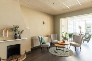 een woonkamer met een open haard en een tafel en stoelen bij Hotel Ameland in Nes