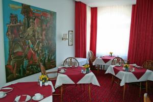 a dining room with two tables with red tablecloths at Hotel Fernblick in Bad Harzburg