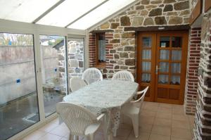 a conservatory with a table and chairs on a patio at gîte marin petit châtelet in Hirel