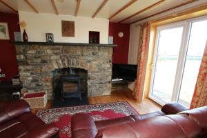 a living room with a stone fireplace and a leather couch at Taigh An Clachair in Lybster