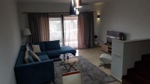 a living room with a blue couch and a tv at City Villa -amazing view in Alepou