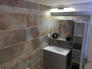 a bathroom with a sink and a tiled wall at T2 climatisé baignoire terrasse Jacuzzi Piscine Sauna in Launaguet