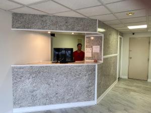 a man standing behind a counter in an office lobby at Red Carpet Inn & Suites - Danville in Danville