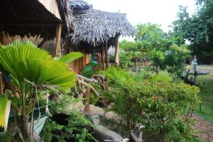 una casa con techo de paja y algunas plantas en Nature Beach Huts en Trincomalee