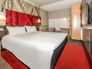 a hotel room with a large white bed with a red rug at ibis Nanterre La Défense in Nanterre