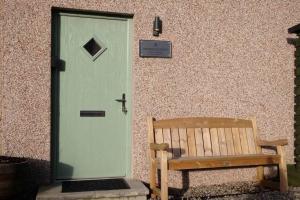 a door with a bench in front of a building at Drumossie Bothy in Inverness