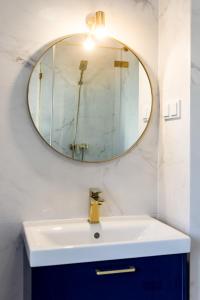 ein Bad mit einem Waschbecken und einem Spiegel in der Unterkunft Apartament BIANCO BLU pod Jasną Górą. in Częstochowa
