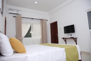 a bedroom with a white bed and a television at Amadel Negombo in Negombo