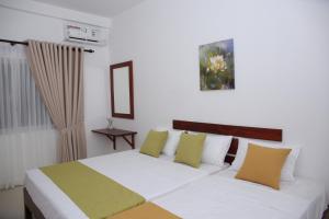 a bedroom with a white bed with yellow and green pillows at Amadel Negombo in Negombo +24 photos