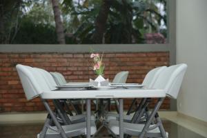 a table with white chairs and a vase of flowers on it at Amadel Negombo in Negombo
