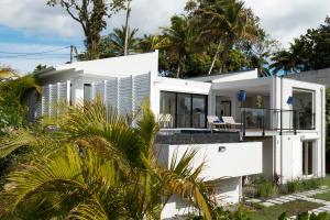 a white house with a balcony and palm trees at So Quiet Villas in Petit-Bourg