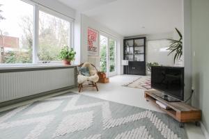 a living room with a flat screen tv and a chair at Vakantiehuis Drie Dennen in Bergen