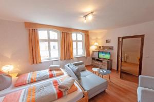 a bedroom with a bed and a couch and a tv at Alte Schule Café und Pension in Fürstlich Drehna
