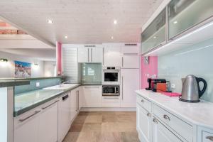 a kitchen with white cabinets and pink walls at Maison Amande in La Flotte