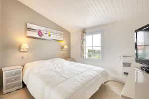 ein weißes Schlafzimmer mit einem Bett und einem Fenster in der Unterkunft Maison Amande in La Flotte