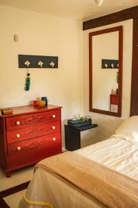 a bedroom with a bed and a dresser and a mirror at Suites de Charme Feiticeira in Ilhabela