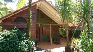 a small green house with a porch and palm trees at Casa Verde, Cahuita in Cahuita