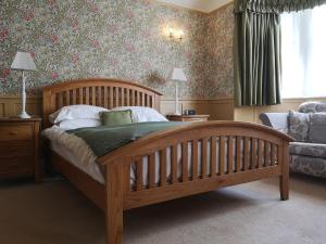 a bedroom with a wooden bed and a couch at Greycroft B&B in Alnwick