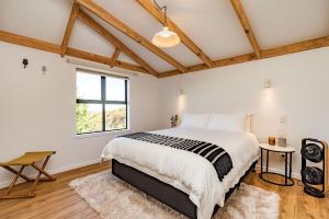 a bedroom with a large bed and a window at Tui & Nikau Cabins in Mangawhai