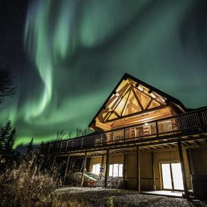 a cabin with the aurora in the sky at Inn on the Lake - Whitehorse in Marsh Lake