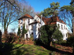 una vieja casa blanca en una colina con árboles en Villa im Reiterdorf en Beverstedt