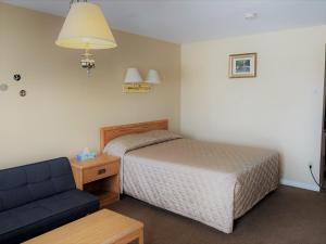 a bedroom with a bed and a blue couch at Hawberry Motel in Little Current