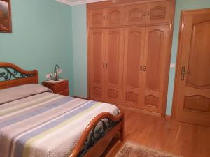 a bedroom with a bed and wooden cabinets at Despertar con el sonido de los pajaros in Melide