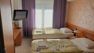 a hotel room with two beds and a flat screen tv at Guest House Boska in Pančevo