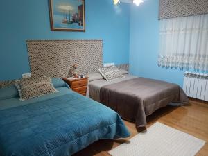 a bedroom with two beds and a blue wall at Despertar con el sonido de los pajaros in Melide