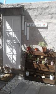 uma porta branca com vasos de plantas ao lado de um edifício em La Casita em Neuquén