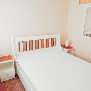 a white bed in a white bedroom with a bed frame at Blue apartman in Sombor