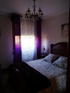 a bedroom with a bed and a chandelier and a window at La Casina in Sevares