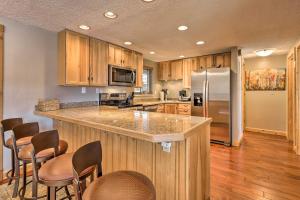 a kitchen with wooden cabinets and a refrigerator and chairs at Steamboat Ski Getaway with Balcony and Resort Views! in Steamboat Springs