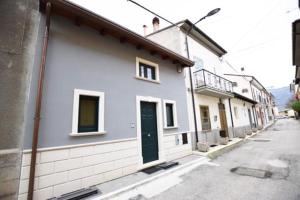 a white building with a green door on a street at ...écche se dòrme in Castelvecchio Subequo