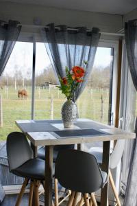 a table and chairs with a vase of flowers on it at Cottage tout confort au milieu des chevaux in Saint-Fargeau +7 photos