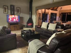 ein Wohnzimmer mit Ledersofas und einem TV in der Unterkunft Twiga Lodge Mabalingwe in Bela-Bela