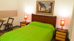 ein Schlafzimmer mit einem grünen Bett mit zwei Tischen und zwei Lampen in der Unterkunft Studios Verdes hospedagens in São Pedro da Aldeia