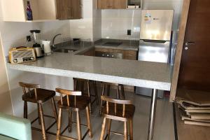 a kitchen with a counter and four bar stools at Departamento en Edificio Costanera Playa Villarrica in Villarrica