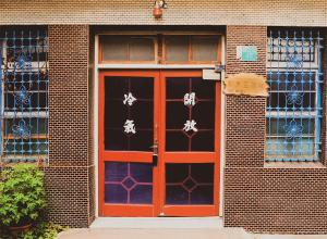 台南市にあるNeat Hostelのレンガ造りの建物の赤い扉