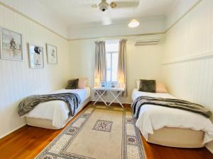 a bedroom with two beds and a rug at Ashbrooke Cottage in Toowoomba